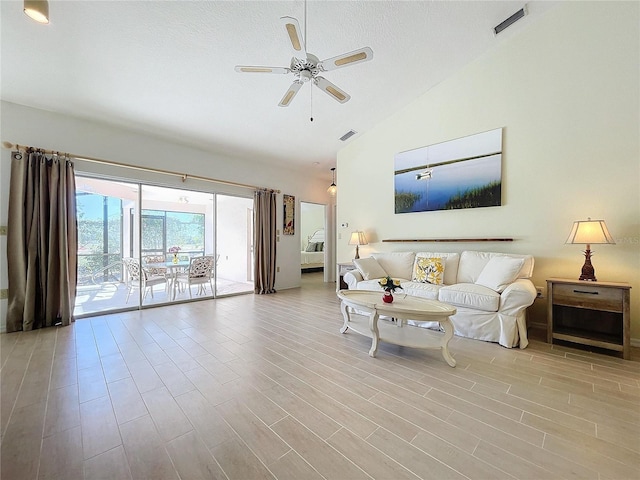 living area with high vaulted ceiling, ceiling fan, visible vents, and wood finished floors