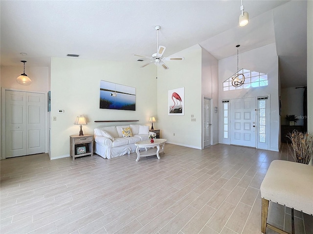 living area with high vaulted ceiling, light wood finished floors, baseboards, and a ceiling fan