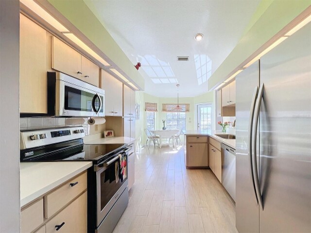 kitchen featuring light wood-style flooring, stainless steel appliances, a peninsula, visible vents, and light countertops