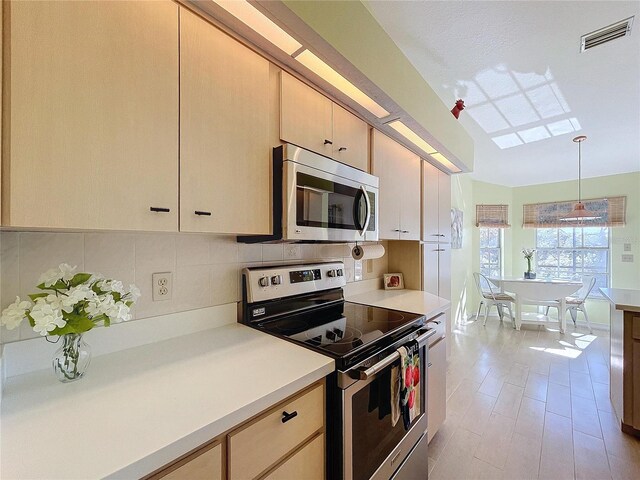 kitchen featuring visible vents, stainless steel appliances, light countertops, pendant lighting, and backsplash