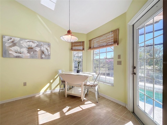 dining area featuring lofted ceiling, wood tiled floor, and baseboards