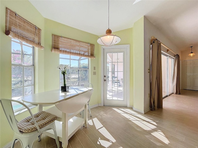 interior space featuring lofted ceiling, light wood-style flooring, and baseboards