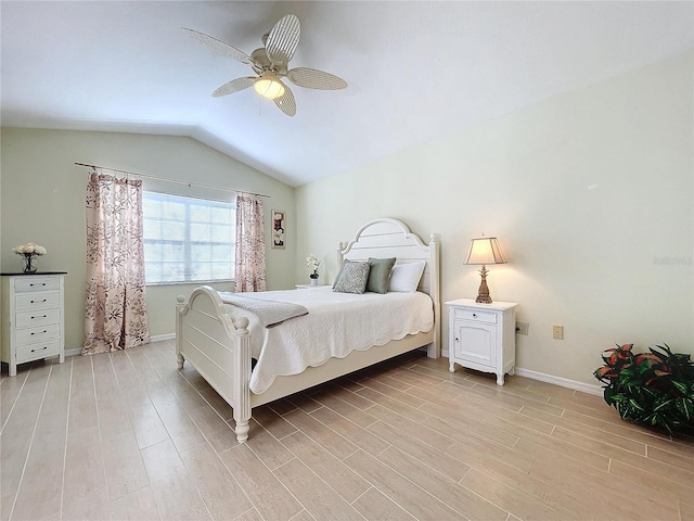 bedroom featuring light wood finished floors, ceiling fan, baseboards, and vaulted ceiling