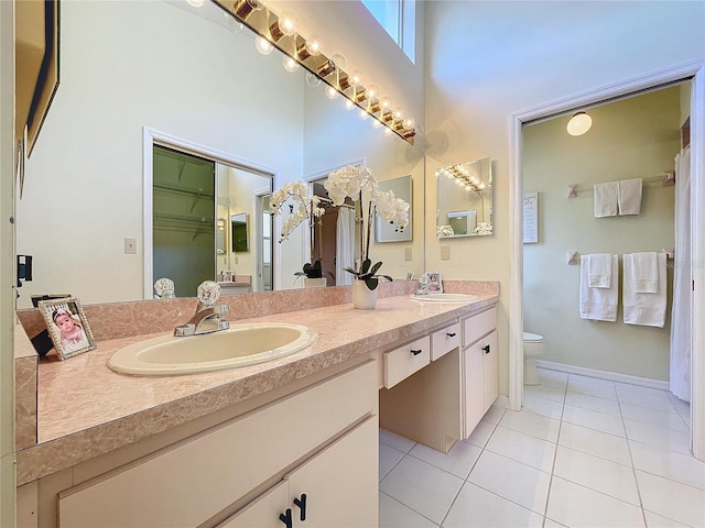 full bath with tile patterned flooring, toilet, a sink, and a high ceiling