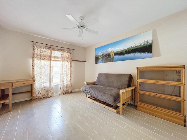 sitting room with ceiling fan, baseboards, and wood finished floors