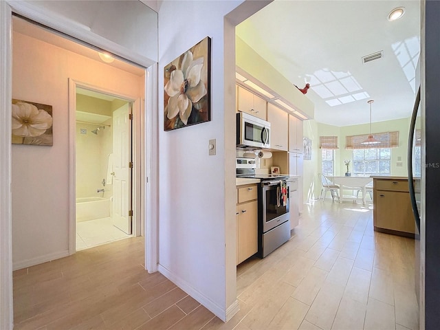 kitchen featuring visible vents, light wood-style flooring, appliances with stainless steel finishes, light countertops, and pendant lighting