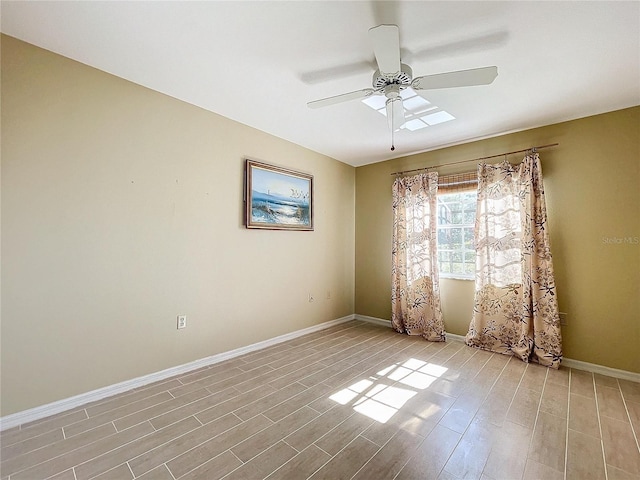 spare room featuring light wood finished floors, baseboards, and a ceiling fan