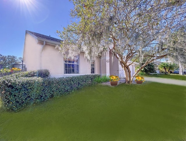 view of side of property with stucco siding and a yard