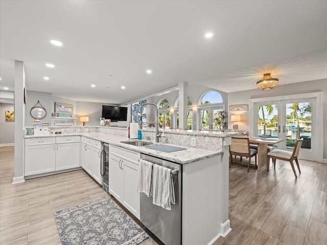 kitchen with french doors, stainless steel dishwasher, sink, light hardwood / wood-style flooring, and white cabinets