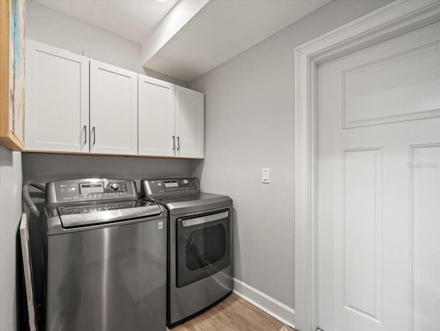 washroom with light hardwood / wood-style floors, cabinets, and washing machine and dryer