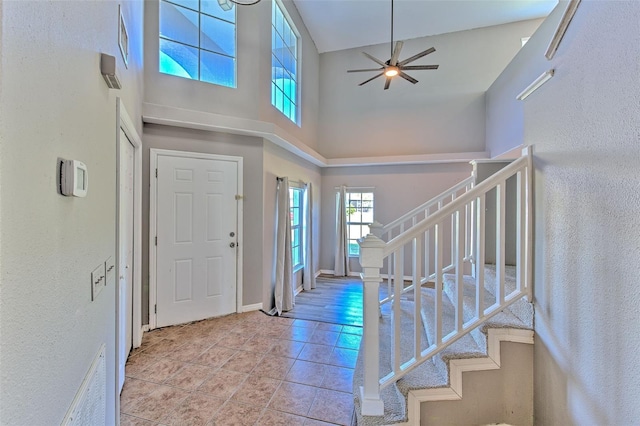 tiled entrance foyer featuring ceiling fan and a towering ceiling