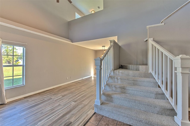 stairs featuring hardwood / wood-style floors and a towering ceiling