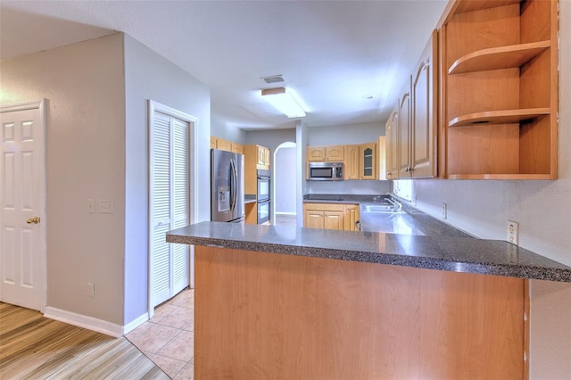 kitchen with light hardwood / wood-style floors, sink, kitchen peninsula, and stainless steel appliances