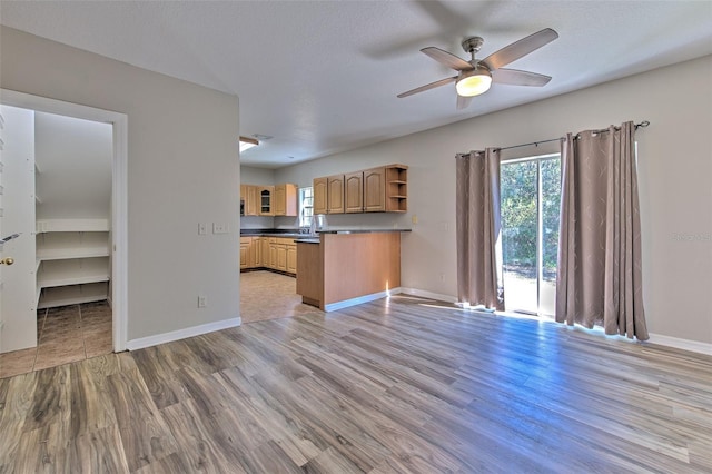 kitchen featuring ceiling fan, kitchen peninsula, a textured ceiling, and light hardwood / wood-style flooring