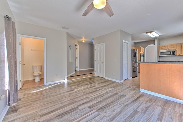 kitchen with light brown cabinetry, stainless steel appliances, ceiling fan, and light hardwood / wood-style floors