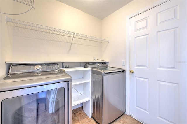 laundry area with washer and clothes dryer and light tile patterned floors