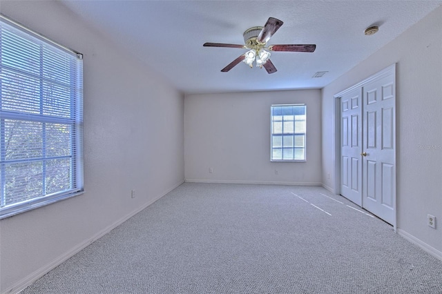 unfurnished bedroom with ceiling fan, light carpet, and a closet