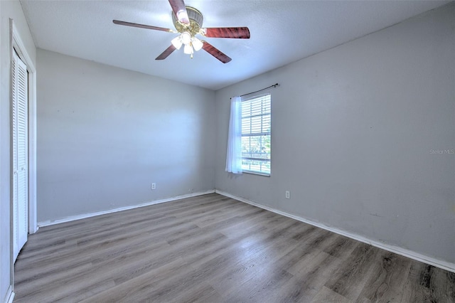 unfurnished bedroom with ceiling fan, wood-type flooring, and a closet