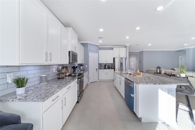 kitchen featuring a kitchen bar, a kitchen island with sink, white cabinets, and stainless steel appliances