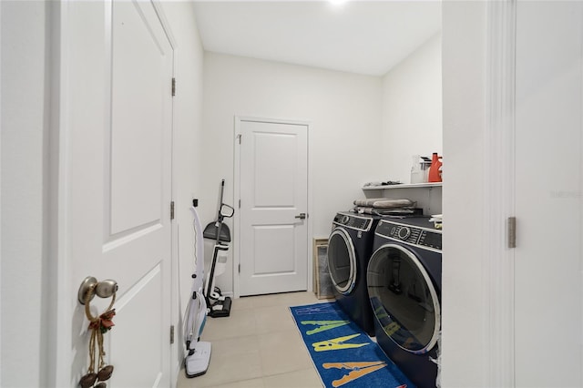 laundry area with independent washer and dryer and light tile patterned floors