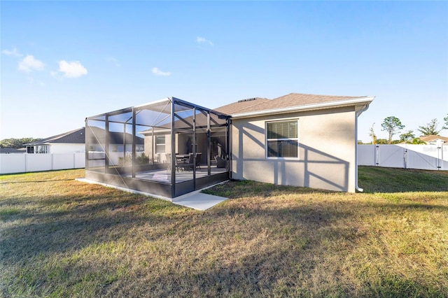 back of house featuring a lawn, glass enclosure, and a patio area