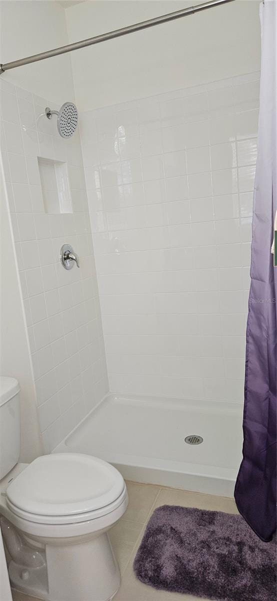 bathroom with curtained shower, tile patterned flooring, and toilet