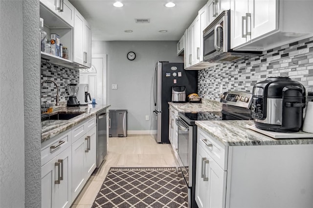 kitchen featuring light stone countertops, sink, white cabinetry, and stainless steel appliances