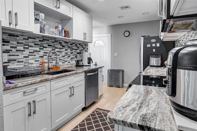 kitchen with light hardwood / wood-style floors, sink, white cabinetry, and stainless steel appliances