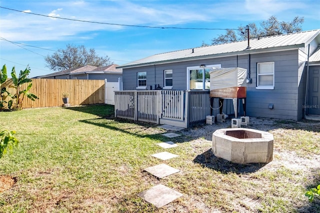 back of property with a fire pit, a deck, and a lawn