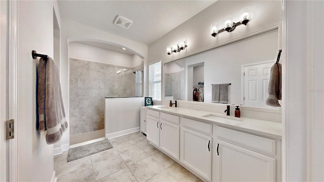 bathroom featuring vanity, a tile shower, tile patterned floors, and a textured ceiling