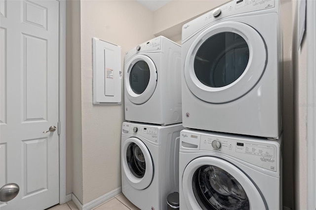 clothes washing area featuring light tile patterned floors and stacked washer and clothes dryer