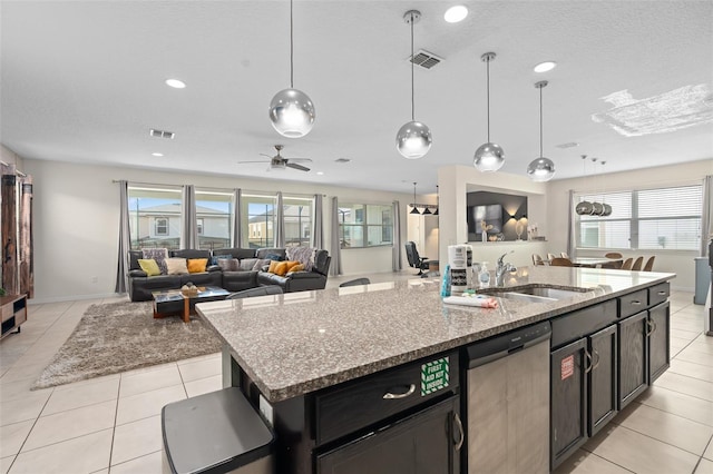 kitchen featuring dishwasher, a kitchen island with sink, hanging light fixtures, ceiling fan, and light stone countertops