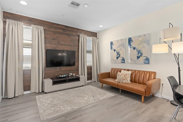 living room with wooden walls and light hardwood / wood-style floors