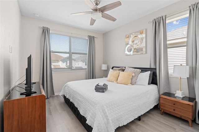 bedroom with ceiling fan, light hardwood / wood-style flooring, and multiple windows