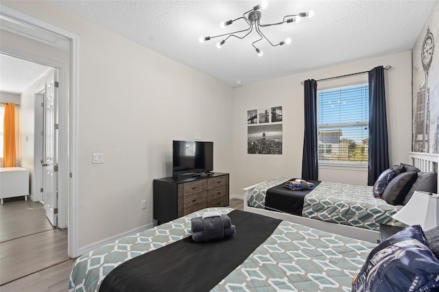 bedroom featuring hardwood / wood-style floors, a textured ceiling, and an inviting chandelier