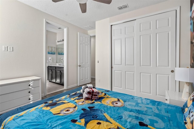 bedroom with ensuite bath, ceiling fan, a textured ceiling, a closet, and light wood-type flooring