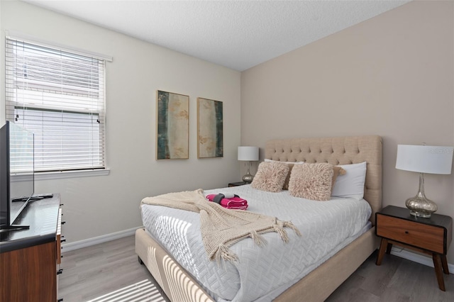 bedroom with a textured ceiling and light hardwood / wood-style floors