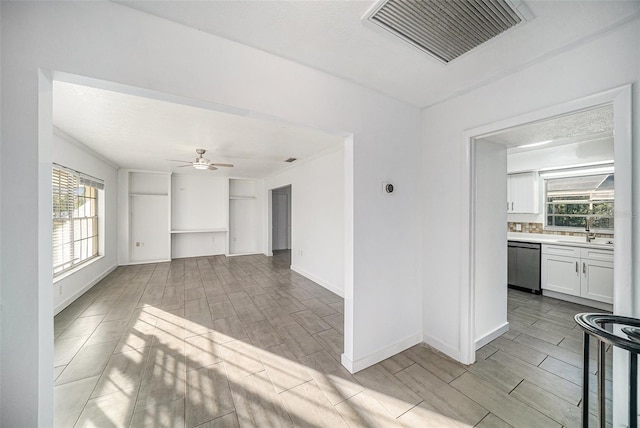 unfurnished living room featuring plenty of natural light, light hardwood / wood-style floors, sink, and ceiling fan