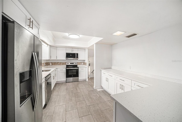 kitchen featuring light stone countertops, white cabinetry, sink, stainless steel appliances, and light hardwood / wood-style flooring