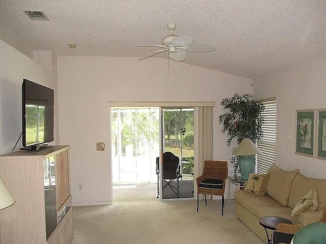 living area featuring a textured ceiling, light colored carpet, vaulted ceiling, and ceiling fan