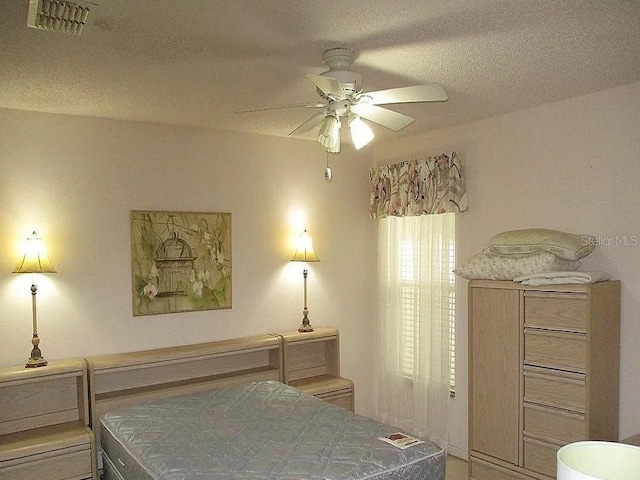 bedroom with ceiling fan and a textured ceiling