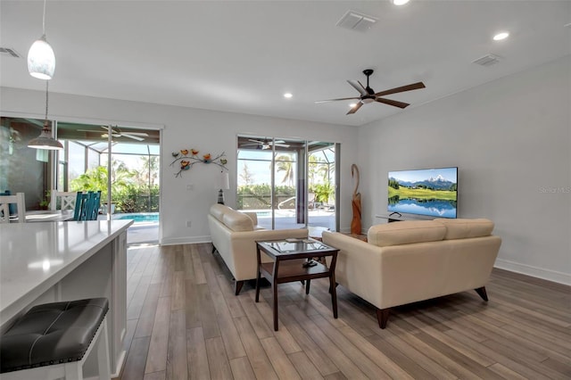 living room with ceiling fan, light hardwood / wood-style flooring, and a wealth of natural light