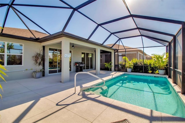 view of pool with a patio, glass enclosure, ceiling fan, and grilling area