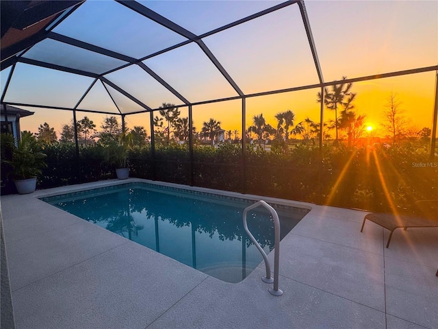 pool at dusk featuring a lanai and a patio area