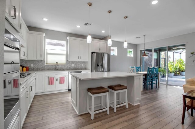 kitchen featuring white cabinetry, appliances with stainless steel finishes, a center island, and pendant lighting