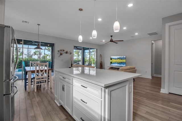 kitchen featuring a center island, pendant lighting, white cabinets, and stainless steel refrigerator