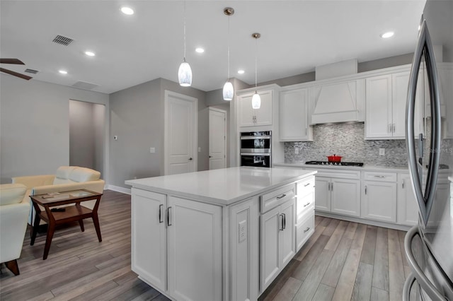 kitchen with decorative light fixtures, stainless steel appliances, and white cabinets