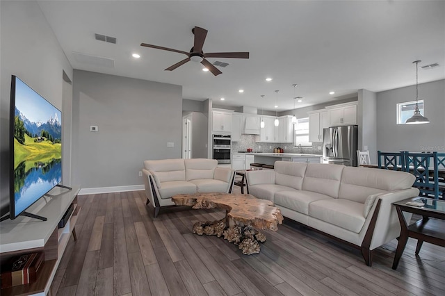 living room with dark wood-type flooring, ceiling fan, and sink