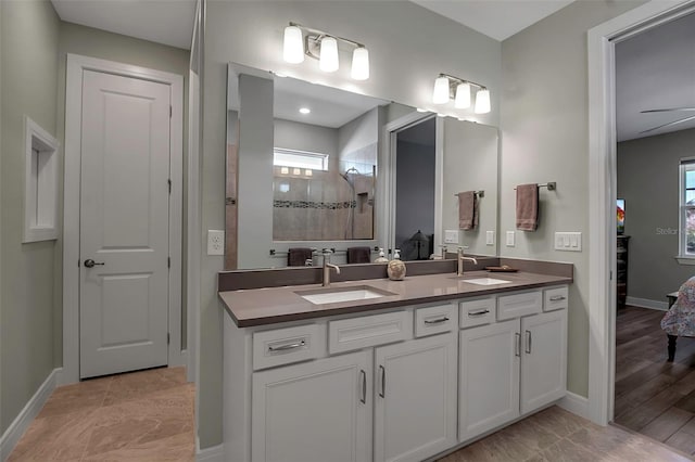 bathroom with a tile shower, vanity, and a healthy amount of sunlight