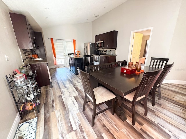 dining area with vaulted ceiling and light wood-type flooring